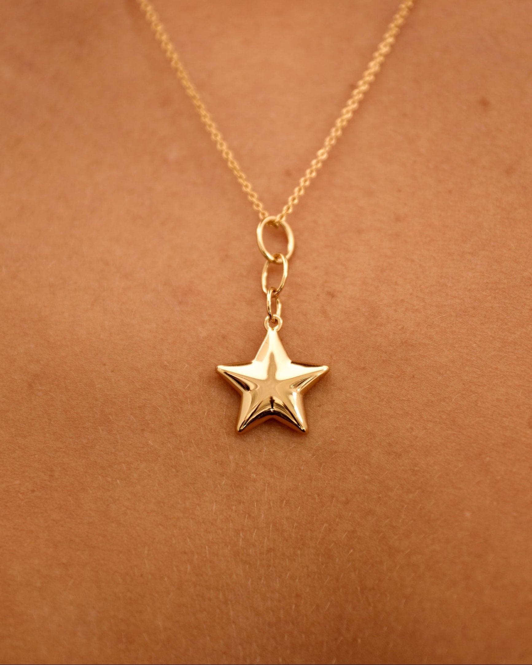 Gold star necklace on a person's neck against a brown background