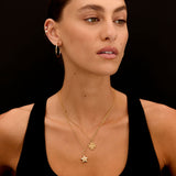 Woman wearing a gold necklace with star pendant on a black background