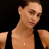 Woman wearing a black top and gold jewelry against a black background