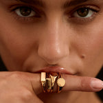 Close-up of a person wearing a gold ring on their finger with a blurred background