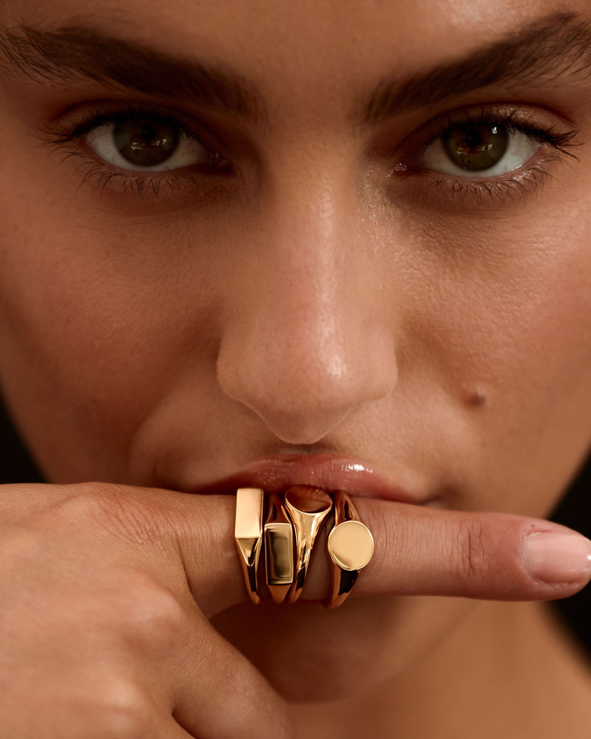 Close-up of a person wearing a gold ring on their finger with a blurred background