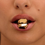 Close-up of a person wearing a gold lip ring with a black background