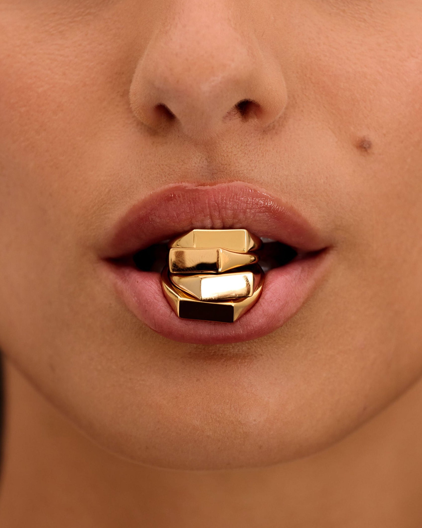 Close-up of a person wearing a gold lip ring with a black background