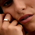 Close-up of a person wearing gold rings with a soft focus on the face.