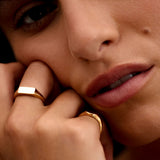Close-up of a person wearing gold rings with a soft focus on the face.