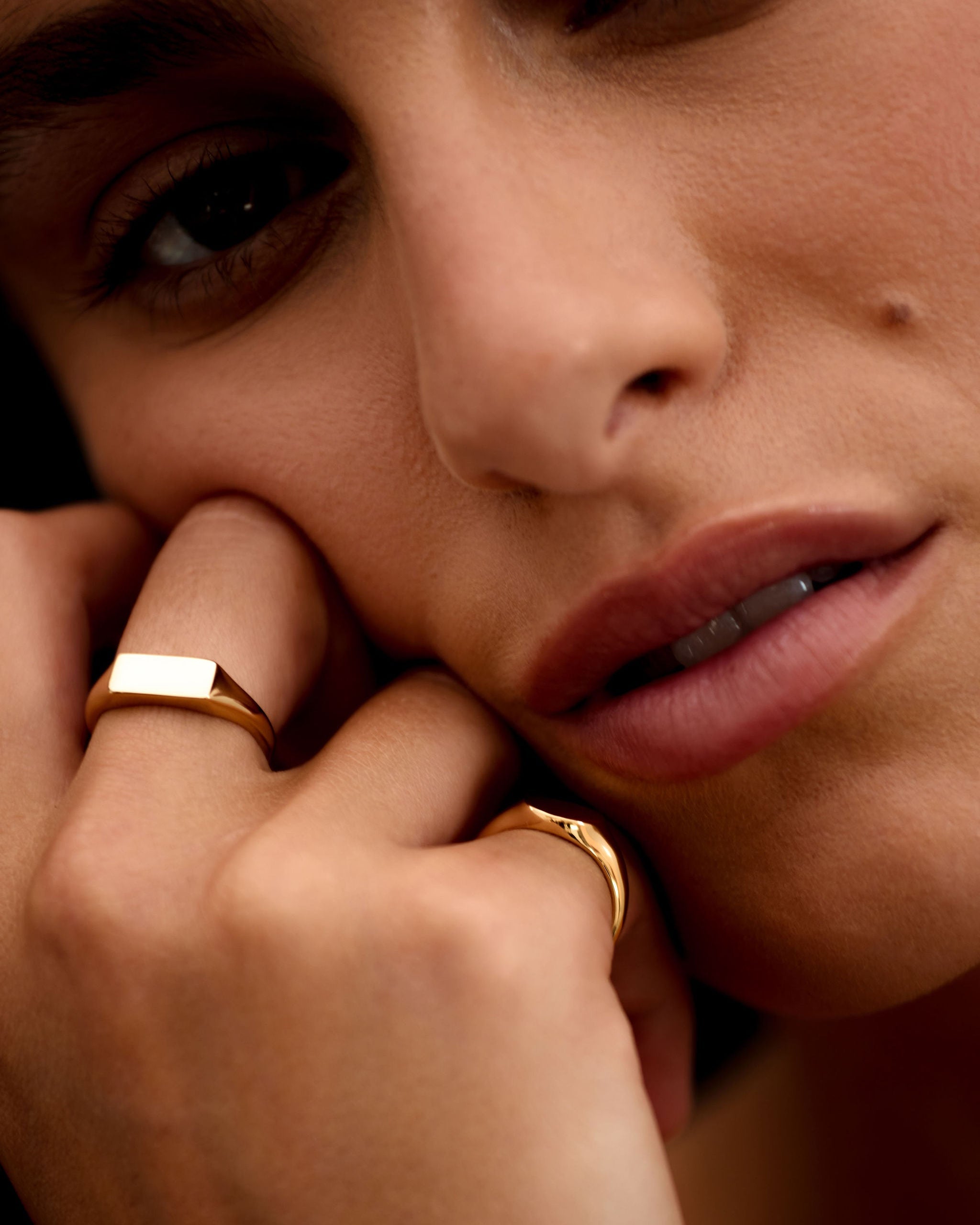 Close-up of a person wearing gold rings with a soft focus on the face.