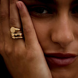 Close-up of a person wearing a gold ring on their finger, with a blurred background.