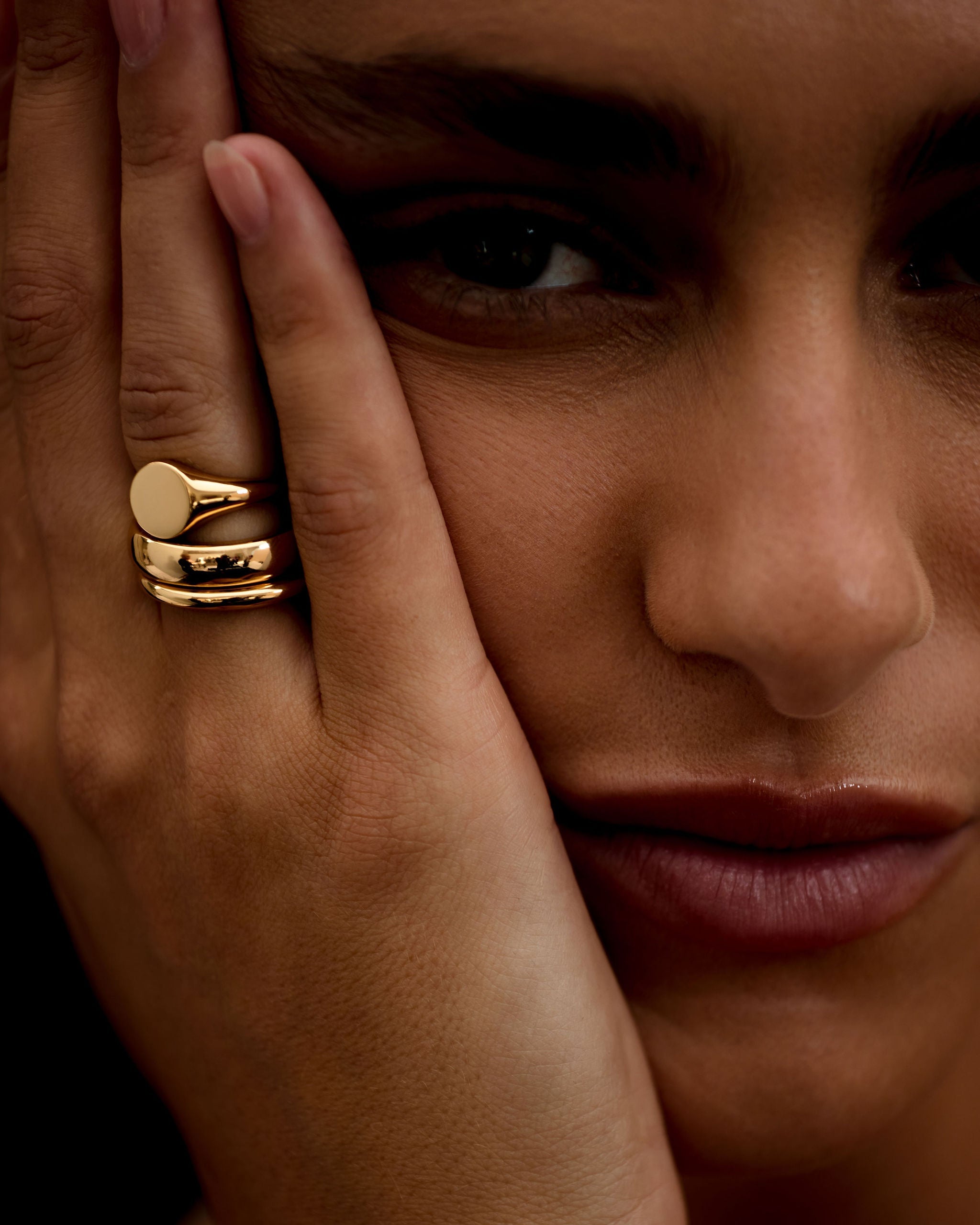 Close-up of a person wearing a gold ring on their finger, with a blurred background.