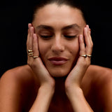 Woman with hands on face against a black background
