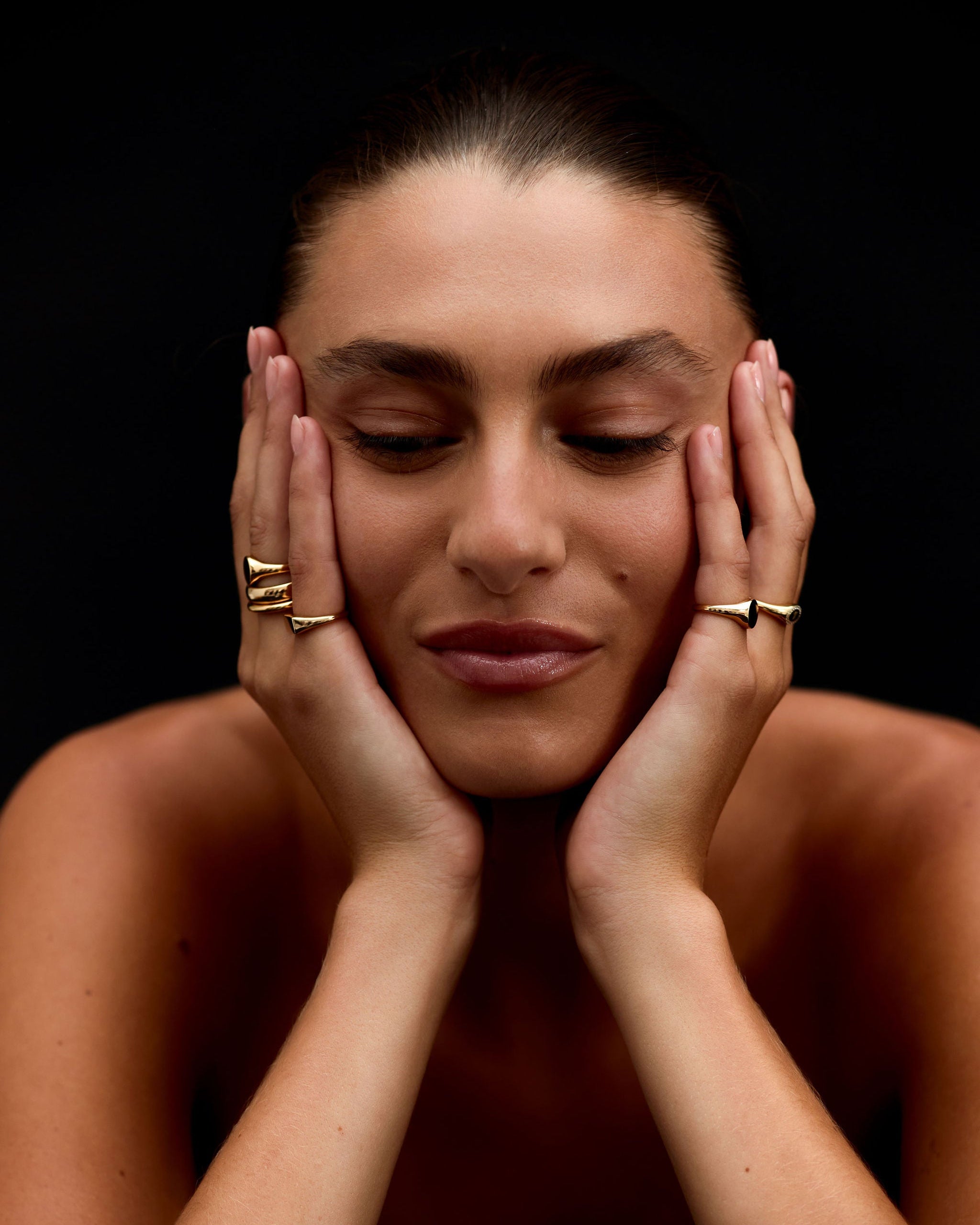 Woman with hands on face against a black background