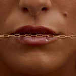 Close-up of a person's mouth with a gold chain over it