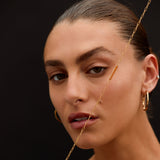 Close-up of a woman with gold jewelry against a dark background