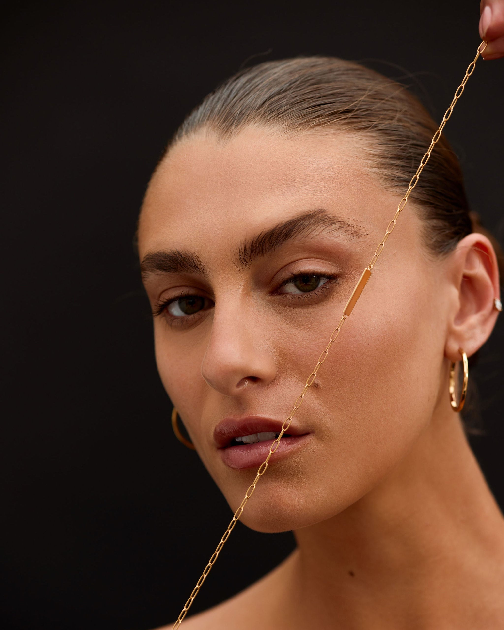 Close-up of a woman with gold jewelry against a dark background