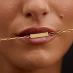 Close-up of a woman's face with a gold bar necklace.