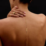 Person wearing a gold body chain with visible jewelry on a black background
