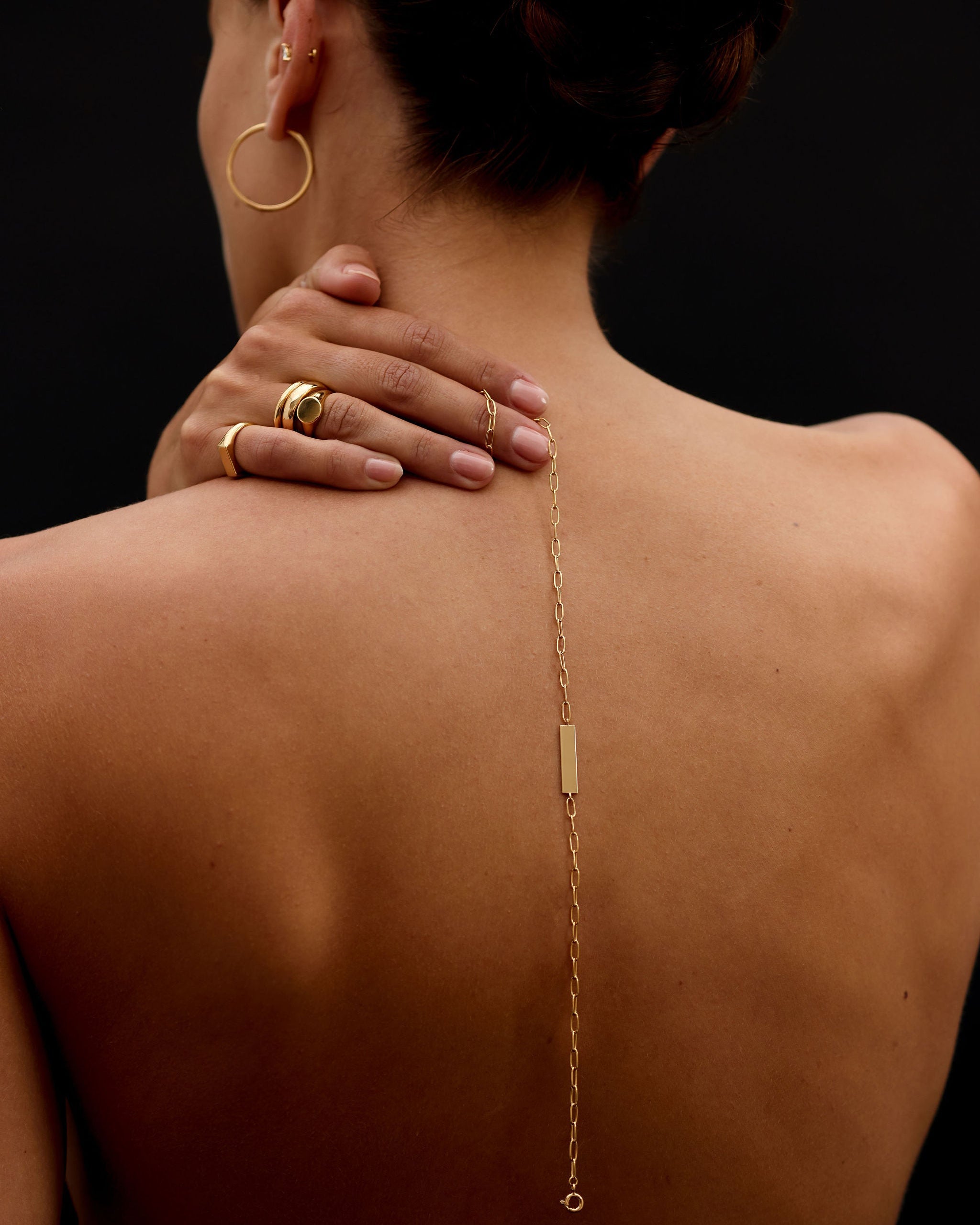 Person wearing a gold body chain with visible jewelry on a black background