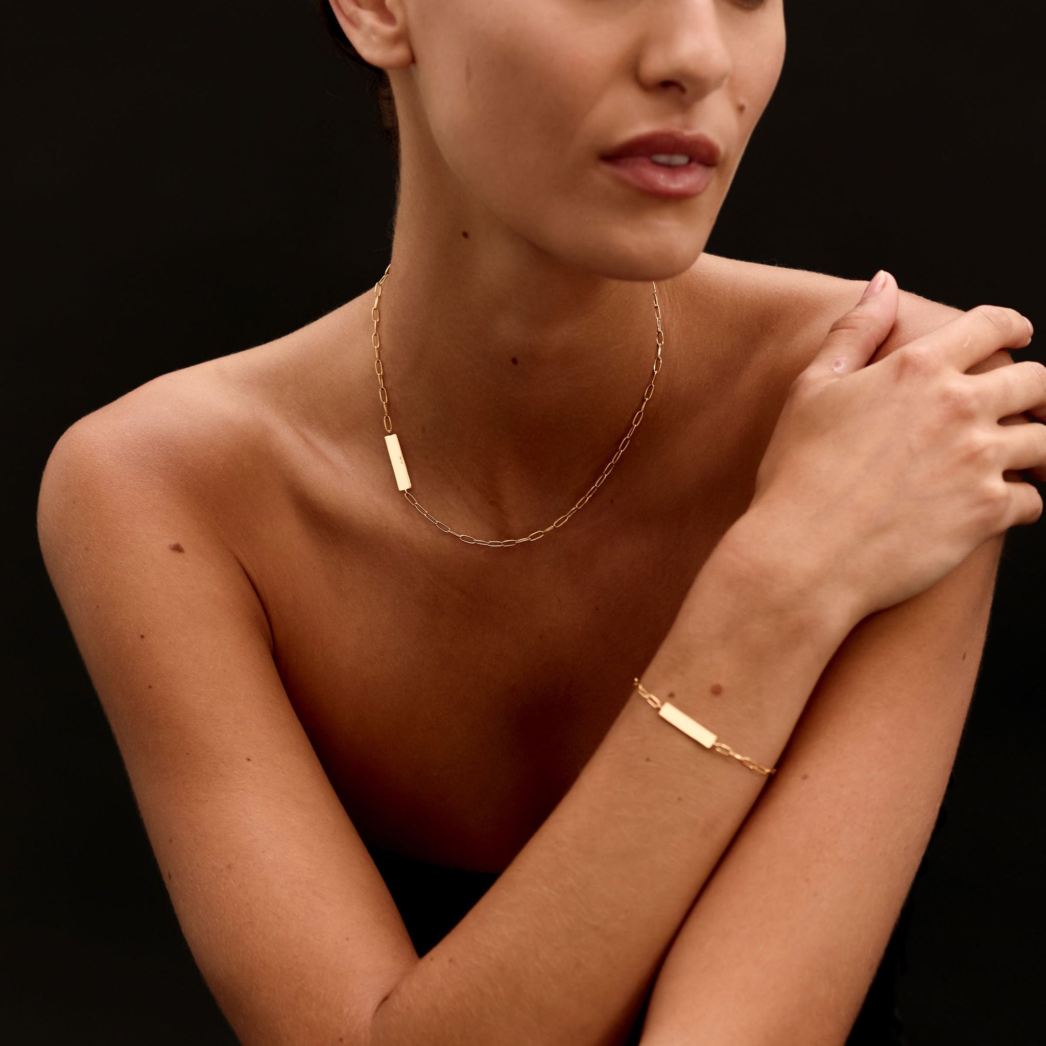 Woman wearing gold jewelry against a dark background