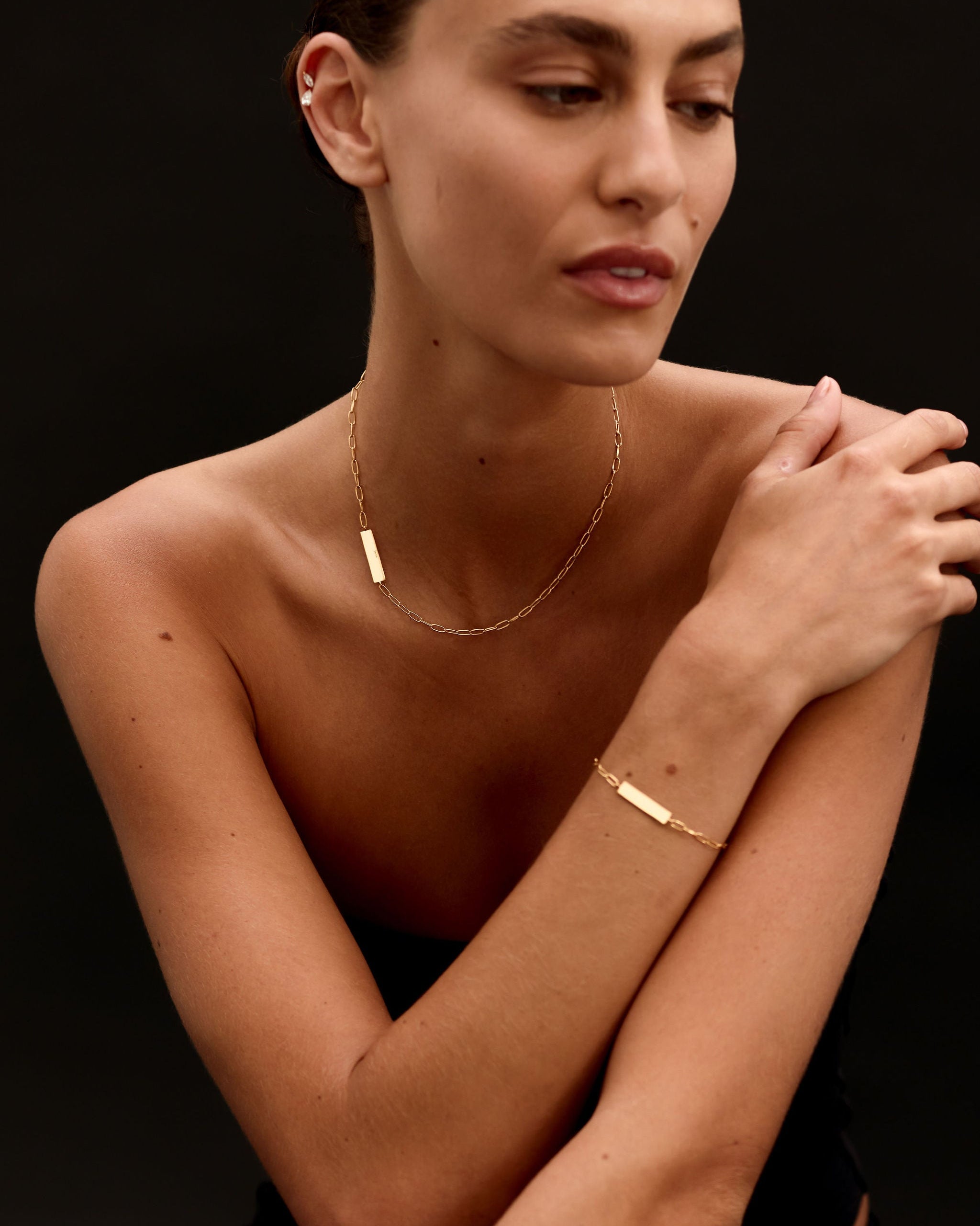 Woman wearing gold jewelry against a dark background