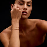 Woman with a gold bracelet on her wrist against a black background