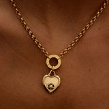 Gold necklace with a heart-shaped pendant on a person's neck