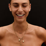 Woman wearing a gold necklace with heart and star charms on a black background