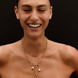 Woman wearing a gold necklace with heart and star charms on a black background