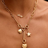 Gold necklace with heart and star charms on a person's neck against a black background