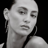 Black and white portrait of a woman wearing hoop earrings against a black background