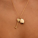 Gold necklace with heart and key pendants on a person's neck