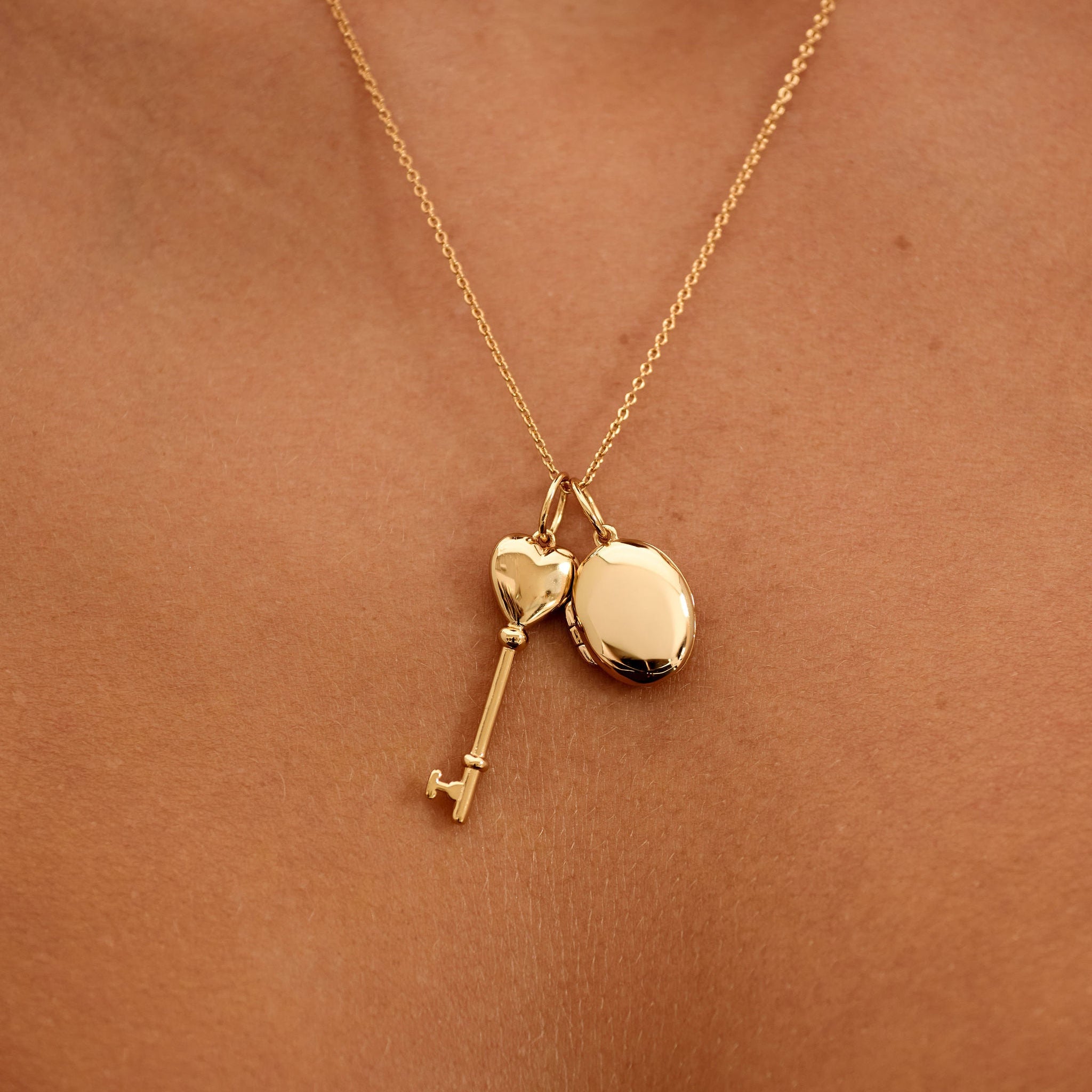 Gold necklace with heart and key pendants on a person's neck