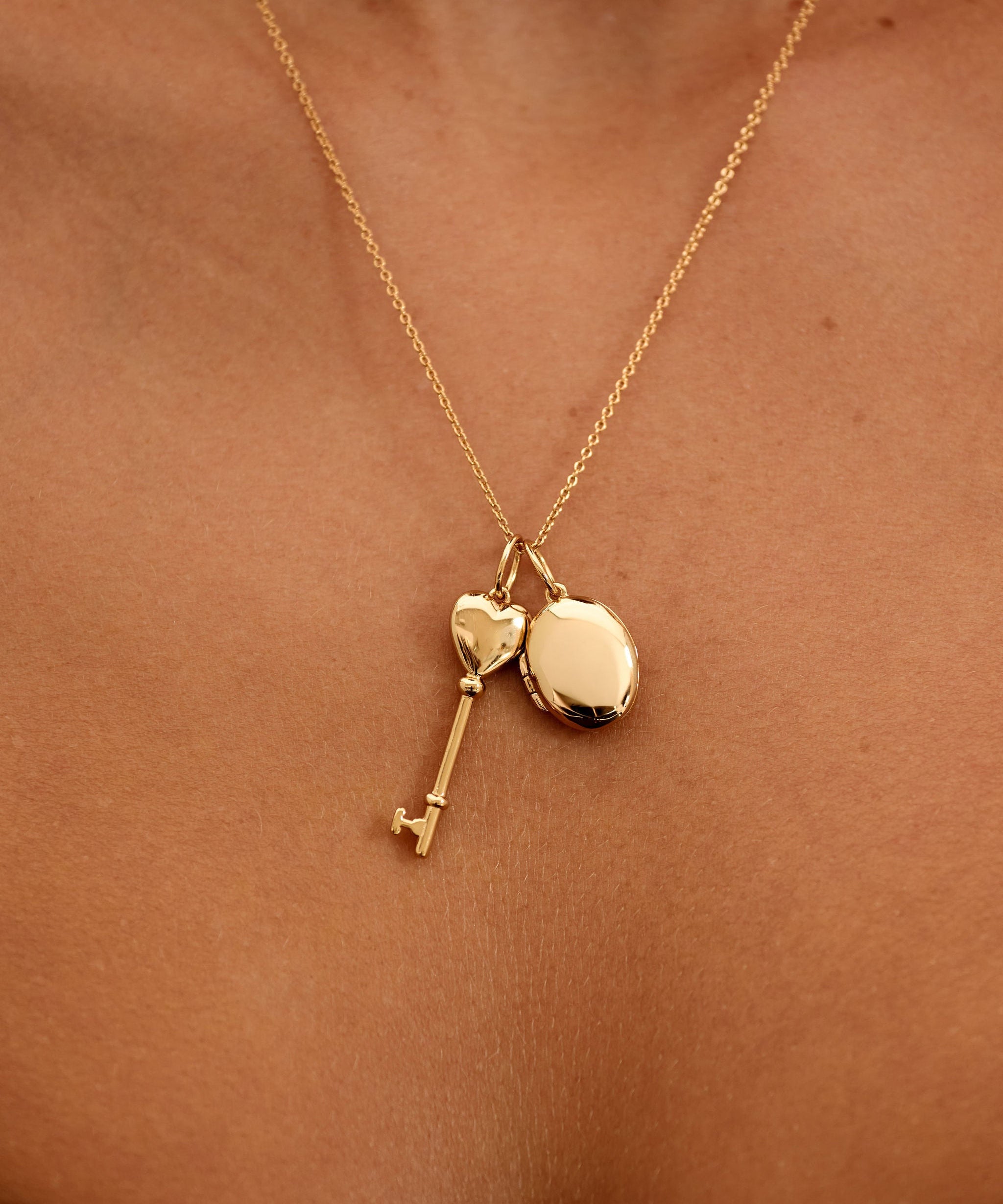 Gold necklace with heart and key pendants on a person's neck