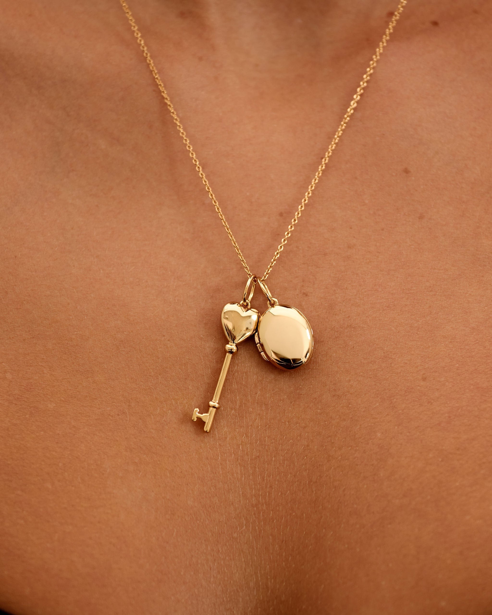 Gold necklace with heart and key pendants on a person's neck