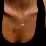 Gold necklace with a heart and key pendant on a person's neck against a black background