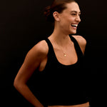 Woman wearing a black tank top and jeans against a black background